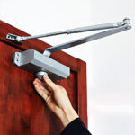Silver commercial hydraulic door closer mounted overhead on a door