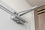 Commercial hydraulic door closer fitted to the top of a door frame with adjustable arm