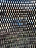 Looking out through black DVA privacy mesh from inside a house, with the outdoor scene clearly visible