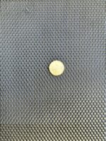 Black DVA privacy mesh with an Australian dollar coin on it for scale, showing 2.2mm louvred openings on 5mm pitch