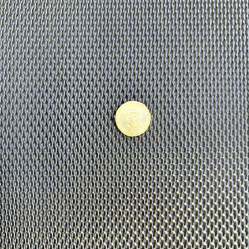 Black DVA privacy mesh with an Australian dollar coin on it for scale, showing 2.2mm louvred openings on 5mm pitch