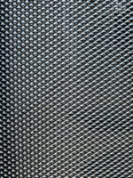 Macro close-up of black DVA privacy mesh showing angled louvred openings with raised lips in tight diagonal rows