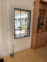 TradeBase 316 marine grade stainless steel flyscreen mesh installed in a white timber screen door with black steel glazing bars, exterior view