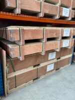 Crates of black perforated aluminium security mesh sheets stacked in the TradeBase Melbourne warehouse