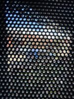 Looking out through black perforated aluminium security mesh from inside a house to sky, houses and a street